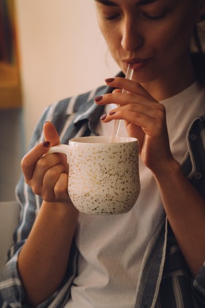 Young pretty woman sitting in a cafe and talking on the phone. The girl drinks hot coffeeの写真素材