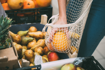 Woman with mesh bag full of fresh vegetables shopping at the store, zero waste conceptの写真素材