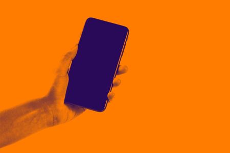 Female hand holding black cellphone with white screen at isolated background.の写真素材