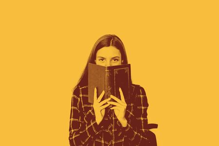 pretty teenager girl student with book in her hands hiding face with copy spaceの写真素材