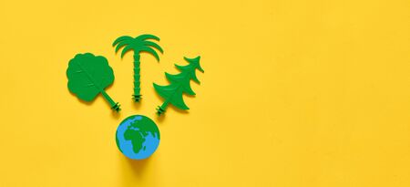 Green trees on yellow background flat lay with copy space. Environment ecology ideaの写真素材