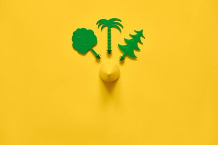 Green trees on yellow background flat lay with copy space. Environment ecology idea