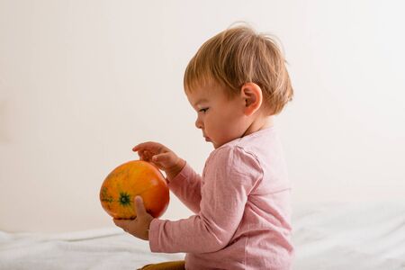 Cute little girl hugging a pumpkin on a bed indoors. copy space