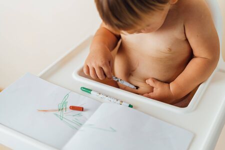 Little toddler baby plays with felt tip pens, drawing colorful lines on the belly. Funny childhoodの写真素材