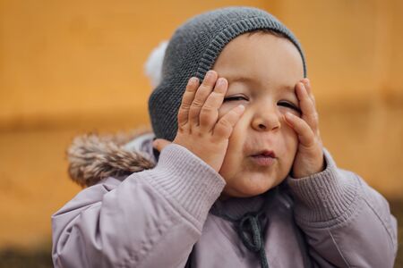 Baby girl surprised with hands on her head. Outddors winter day. Wowの写真素材