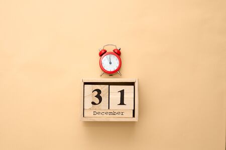 December 31st wooden color calendar on beige background. Flat lay , wooden cubes and alarm clock