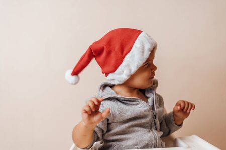 baby in Christmas bonnet looks at camera, on white backgroundの写真素材