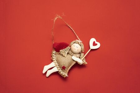 Top view of flying angel decoration on red background. Copy space