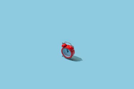 Red alarm clock on pastel blue background. Creative idea. minimal concept. Isometric, harsh lightの写真素材
