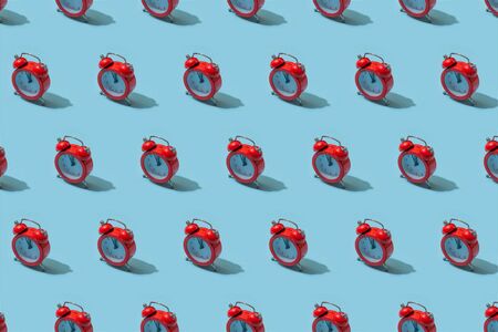 Red alarm clock on pastel blue background. Creative idea. minimal concept. Isometric, harsh lightの写真素材