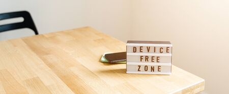 Digital detox day. Lightbox on wooden background and white walls. Gadget ban