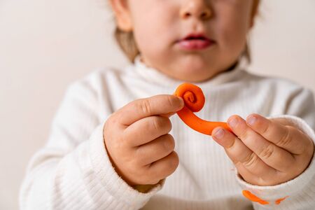 Little toddler plays play dough. Modeling orange sun. Creativity imagination skillの写真素材