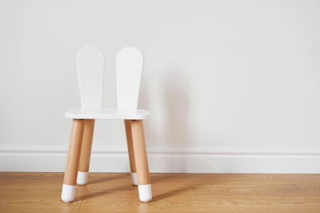 White and wooden child chair with rabbit ears. White wall copy space. Toddler educationの写真素材