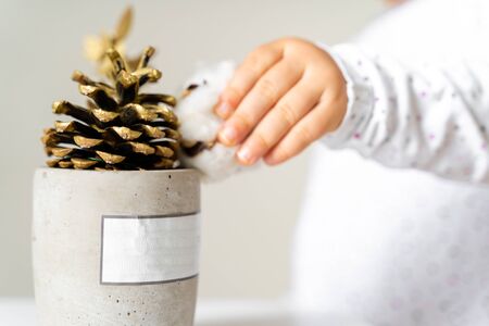 Baby toddler hand decorating with golden pine cone. Christmas. Waldorf natural toysの写真素材
