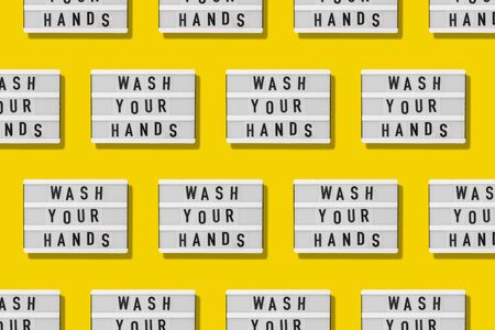 Top view flat lay pattern yellow background. Lightbox with wash your hands text. Covid-19 pandemicの写真素材