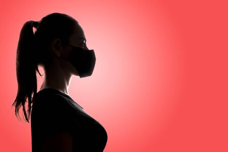 Backlight silhouette portrait of woman wearing mask during pandemic or air pollution. Covid-19 preventionの写真素材