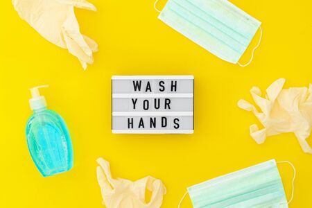 Wash your hands lightbox with medical mask, lighid soap and medical gloves. Top view on yellow...