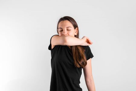 Young woman sneezing to elbow. Pneumonia or virus sickness. Covid-19 pandemicの写真素材