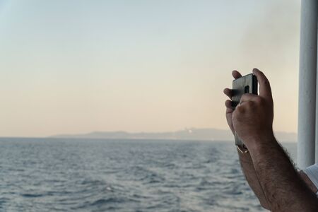 Hands of middle age man with phone doing photo or video. Travel influencer, content creator