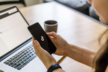 Poltava, Ukraine - June 2020 Phone on the wooden table and with TikTok logo on it.のeditorial素材