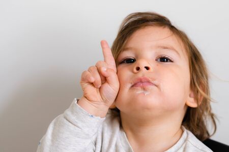 Toddler with one finger upwards. Girl child portrait close up. Lifestyle math learning in preschool