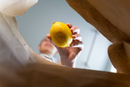 Inside view of craft paper bag with woman puts food in it. Food take away conceptの写真素材