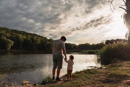 Father and baby girl sitting near lake. Local travel. New normal vacation. Fathers dayの写真素材