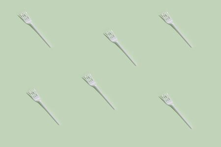 Top view of white plastic forks on pale green background. Trendy isometric pattern with shadows. Ecology pollution. Take out foodの写真素材