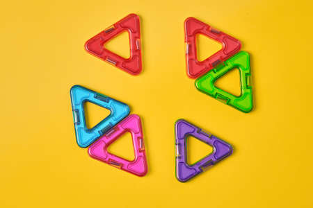 Top view of colorful magnetic building blocks on yellow background