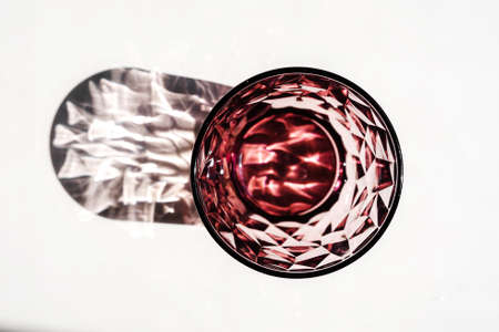 Crystal red glass on white table. Hard shadows in sunlight.の写真素材