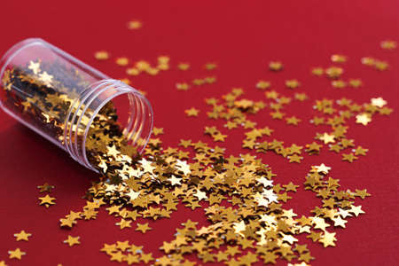 Vertical photo of golden star glitter on red background. Top view. Christmas backgroundの写真素材