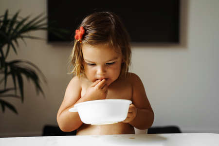 Toddler girl eating cookie and drink juice. Snack food for child. Home lifestyleの写真素材