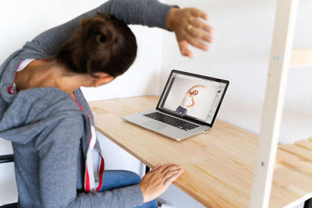 Woman doing stretching yoga at her office by online sport video. Fitness at work.の写真素材