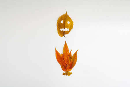 Yellow autumn leaf with halloween face and fire isolated on white background. Spooky minimal holidayの写真素材