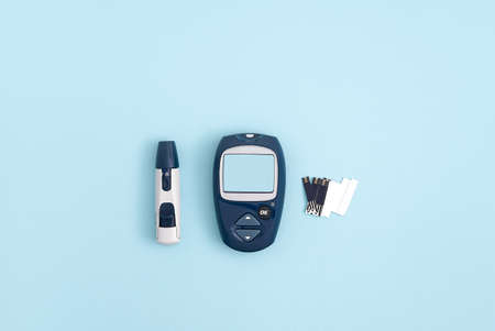 Glucose meter and pen on blue background, top view. Metabolic syndrome conceptの写真素材