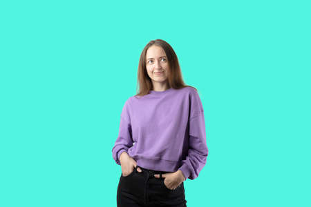 young caucasian woman on turquoise background in purple sweater. Happy millennial girlの写真素材