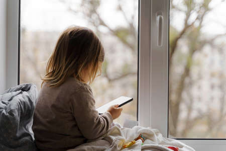 toddler child using phone at home, taking photos and playing gamesの写真素材