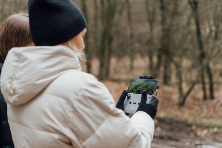 Caucasian woman flying aerial drone in autumn forest. Tech savvy middle age woman. Hobby modern. High quality photoの写真素材