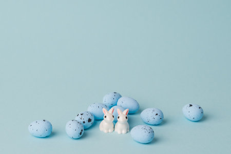 quail blue easter eggs on blue background. Minimal comcept with copy space. spring holidays decor. two white bunniesの写真素材