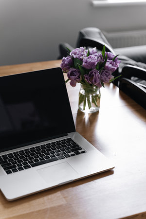 Workplace at home office with laptop and tulips flowers. 8 march. springtime. slow living. mindful work life balance. woman at workの写真素材