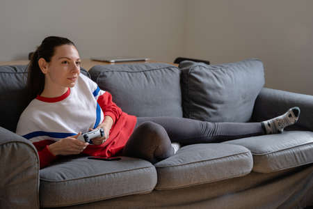woman at home playing video games with wireless gamepad. Console gaming home leisure activity. Millennial home. Quarantine lifestyleの写真素材