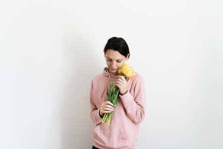 Millennial caucasian woman with bouquet of yellow tulips on white background. Lifestyle portrait of sustainable mindful life. Mothers Day gift, international women day conceptの写真素材