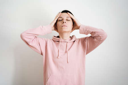 Beautiful young millennial woman doing face yoga at home. Fascial exercises for building youthful sculpted face. Anti-aging self-care routine. Building face muscles conceptの写真素材