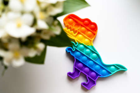 Popit rainbow toy in rainbow colours and dino shape. Trendy bubble pop fidget. Funny anti stress...