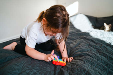 Toddler girl with popit toy in rainbow colours.