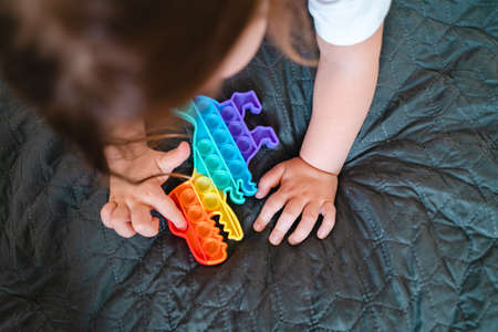 Toddler girl with popit toy in rainbow colours.の写真素材