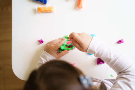 Toddler girl playing plasticine dough in preschool or at home. Creative education, motor skills development. Homeschool concept.の写真素材