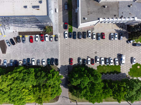 Aerial view of urban parking lot near business center. Top drone point of view. Carpark spot in a...