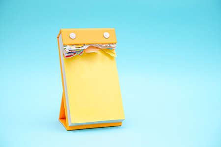 Yellow empty vertical calendar mockup ob blue background. Torn lifestyle template of kids calendar.