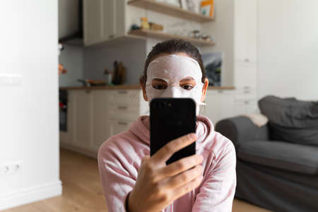 Young woman with beauty mask at home. Snackable wellness concept. Relaxation at home for young mother. Quick face mask for home spa.の写真素材